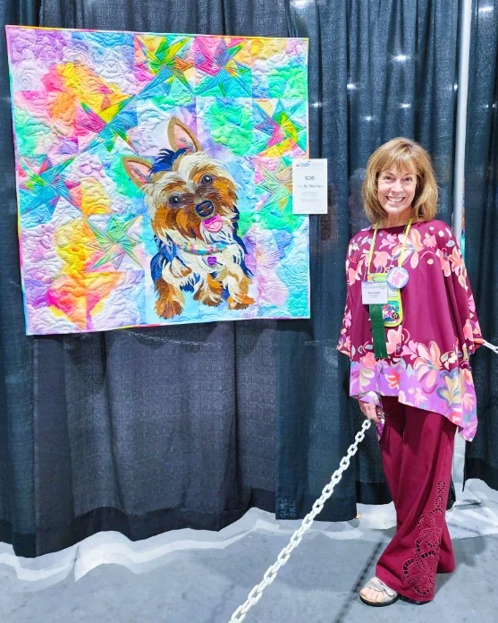 The artist standing next to the quilt at the AQS Daytona Beach Show