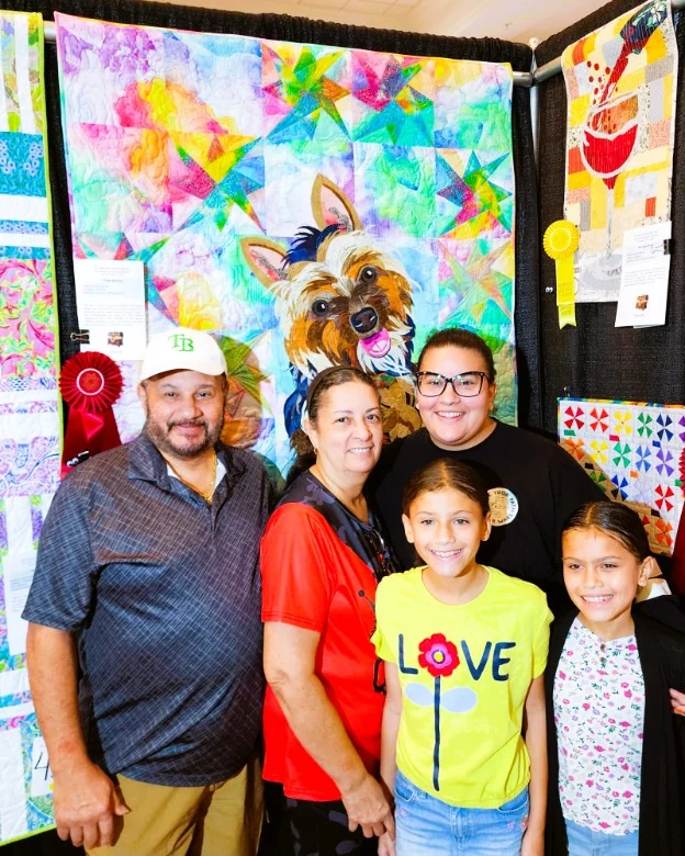 Meredith and her family posing in front of the finished quilt