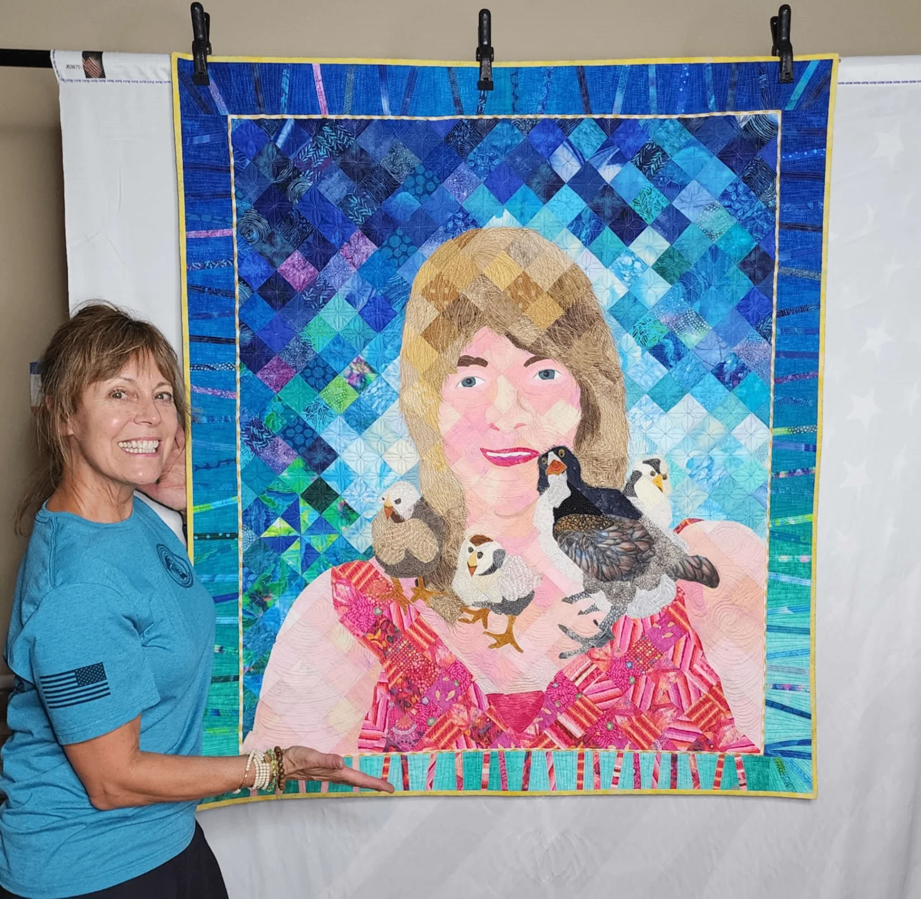Woman standing next to the quilt hanging on a wall
